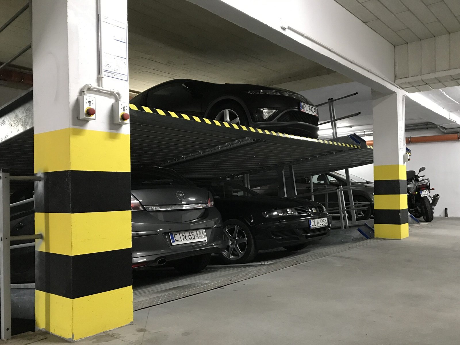 Two-level car stacker parking lift with a car raised on the platform and another parked underneath