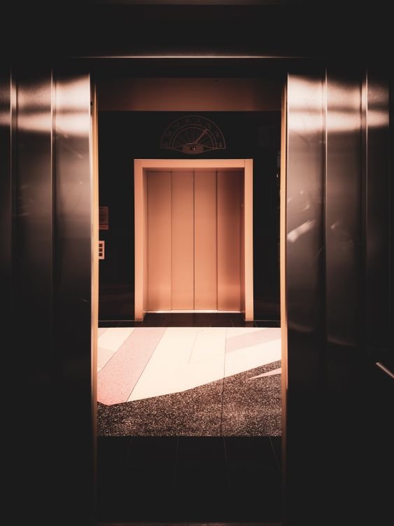 Modern stainless-steel elevator cabin interior with warm lighting and digital floor indicator