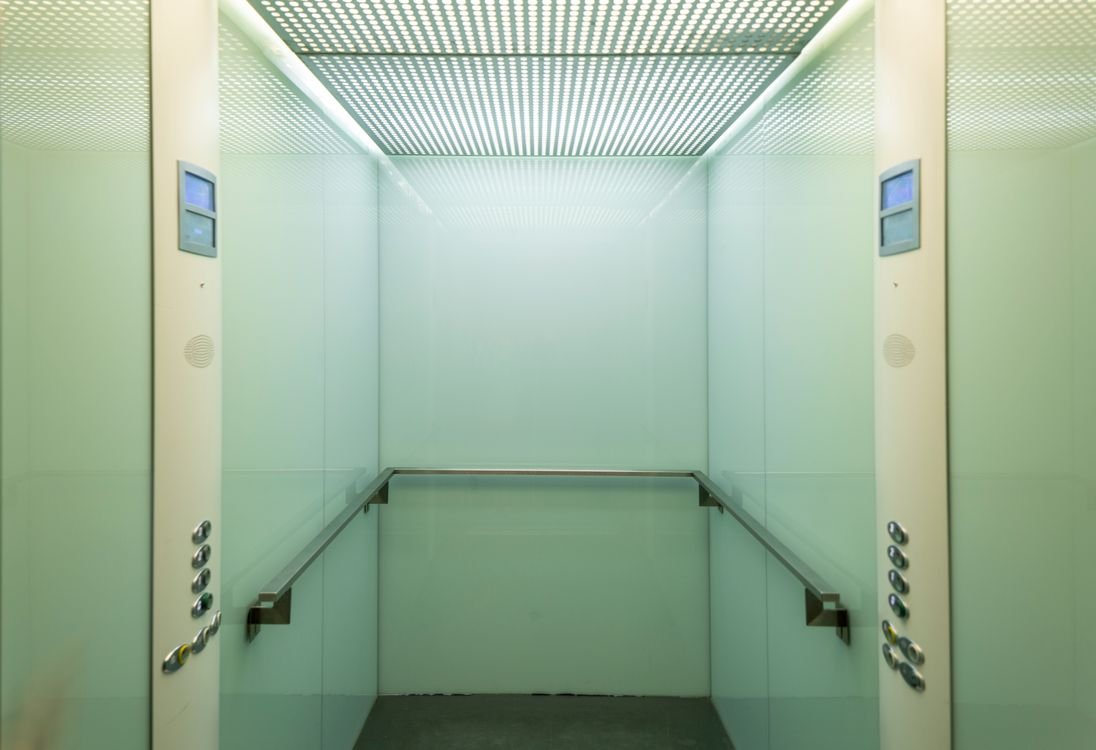 Modern elevator cabin interior with LED ceiling lighting and stainless steel walls
